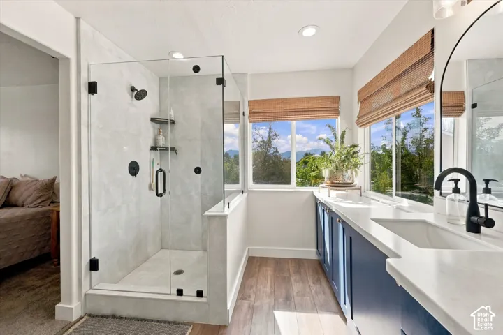 Glass-enclosed shower with dark fixtures and built-in shelving, complemented by wood-finish flooring