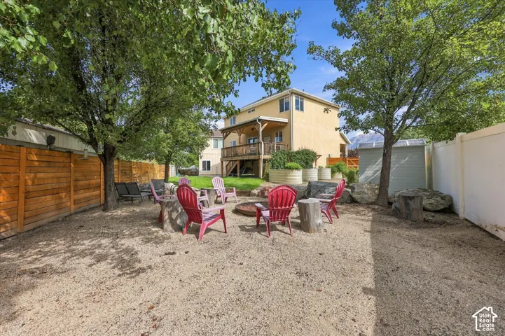 Expansive backyard featuring a gravel surface, mature trees, a wooden privacy fence, and a white fence