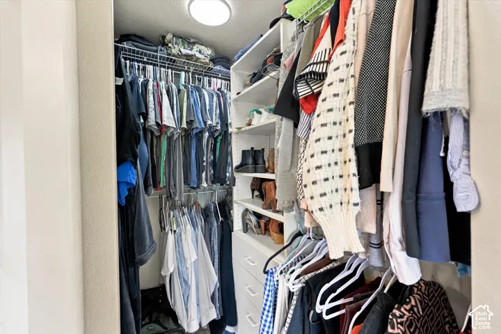 Walk-in closet featuring built-in shelving, multiple hanging rods, and integrated drawers