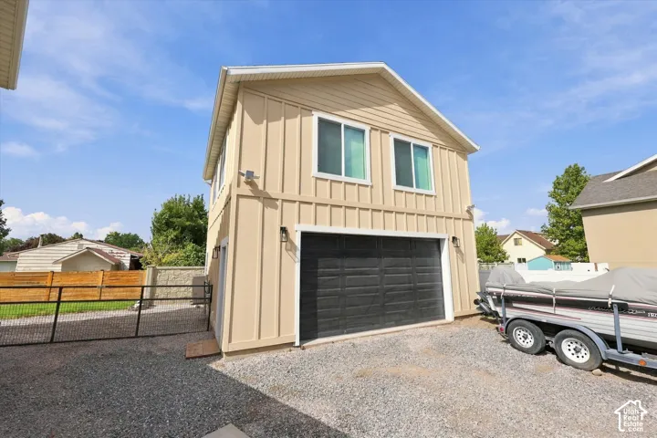 Two-story exterior structure with vertical siding, two upper-level windows, and a black garage door