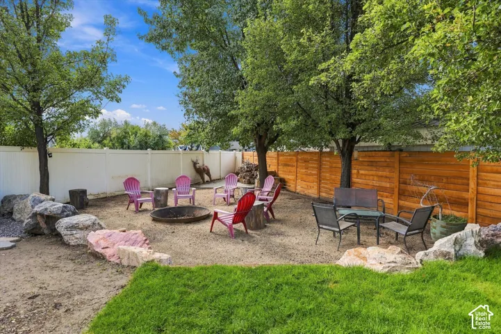 Backyard featuring a fire pit area, mature trees, rock landscaping, and varied privacy fencing