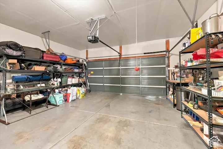 Attached garage featuring a sectional door, concrete flooring, and an automatic garage door opener