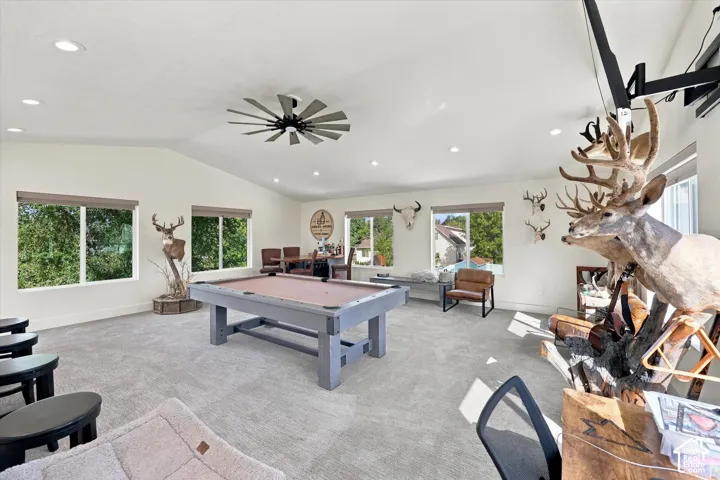 Room above detached garage. Spacious room with vaulted ceilings, recessed lighting, carpeted flooring, multiple large windows, and a ceiling fan