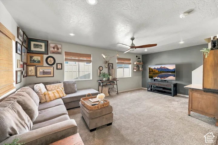 Expansive living area featuring light-colored carpeting and recessed lighting