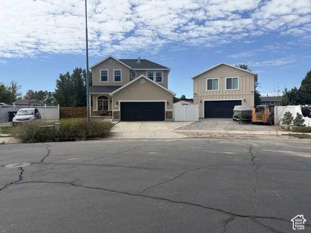 Two-story residence featuring a two-car garage, an additional two-story detached garage with a single bay, a white vinyl fence, and a wooden fence