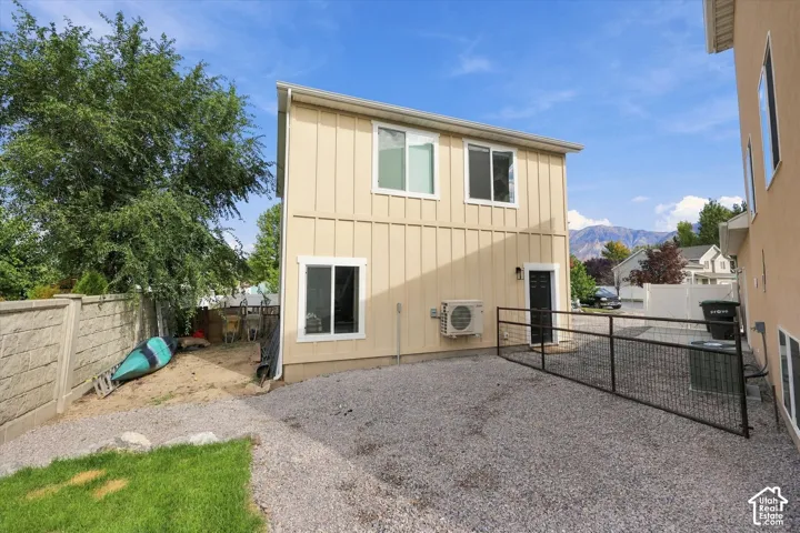 Two-story exterior with board and batten siding, white-trimmed windows, and a gravel parking area