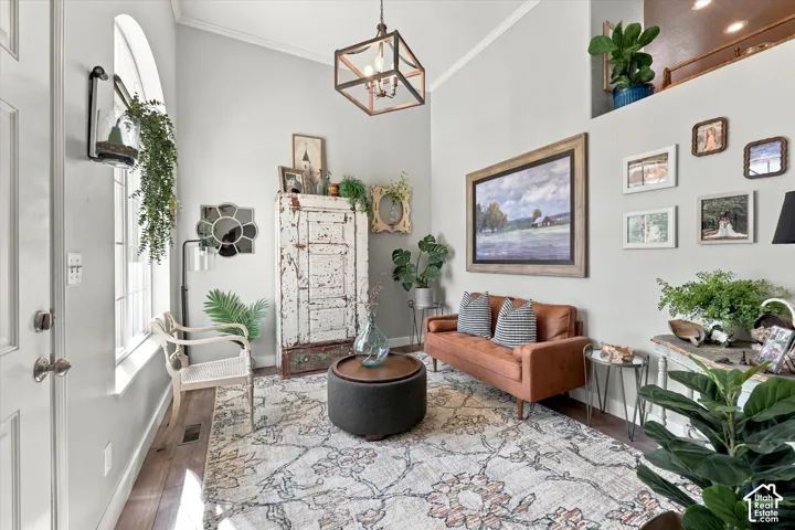 Vaulted ceiling with an exposed beam light fixture, arched window, wood-finish flooring, and light gray wall paint