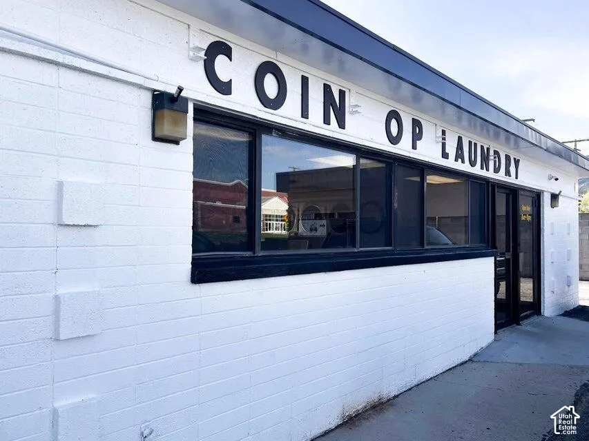 White painted brick exterior with a black awning and multiple front-facing windows
