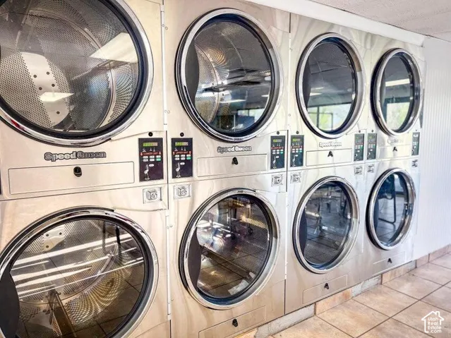 Commercial-grade Speed Queen laundry appliances, multiple washer and dryer units, stainless steel finishes, tile flooring, and integrated control panels