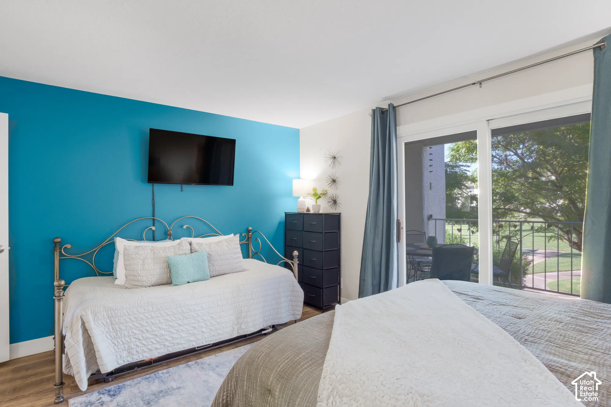Sliding glass door to balcony, featuring wood-finish flooring and a vibrant accent wall