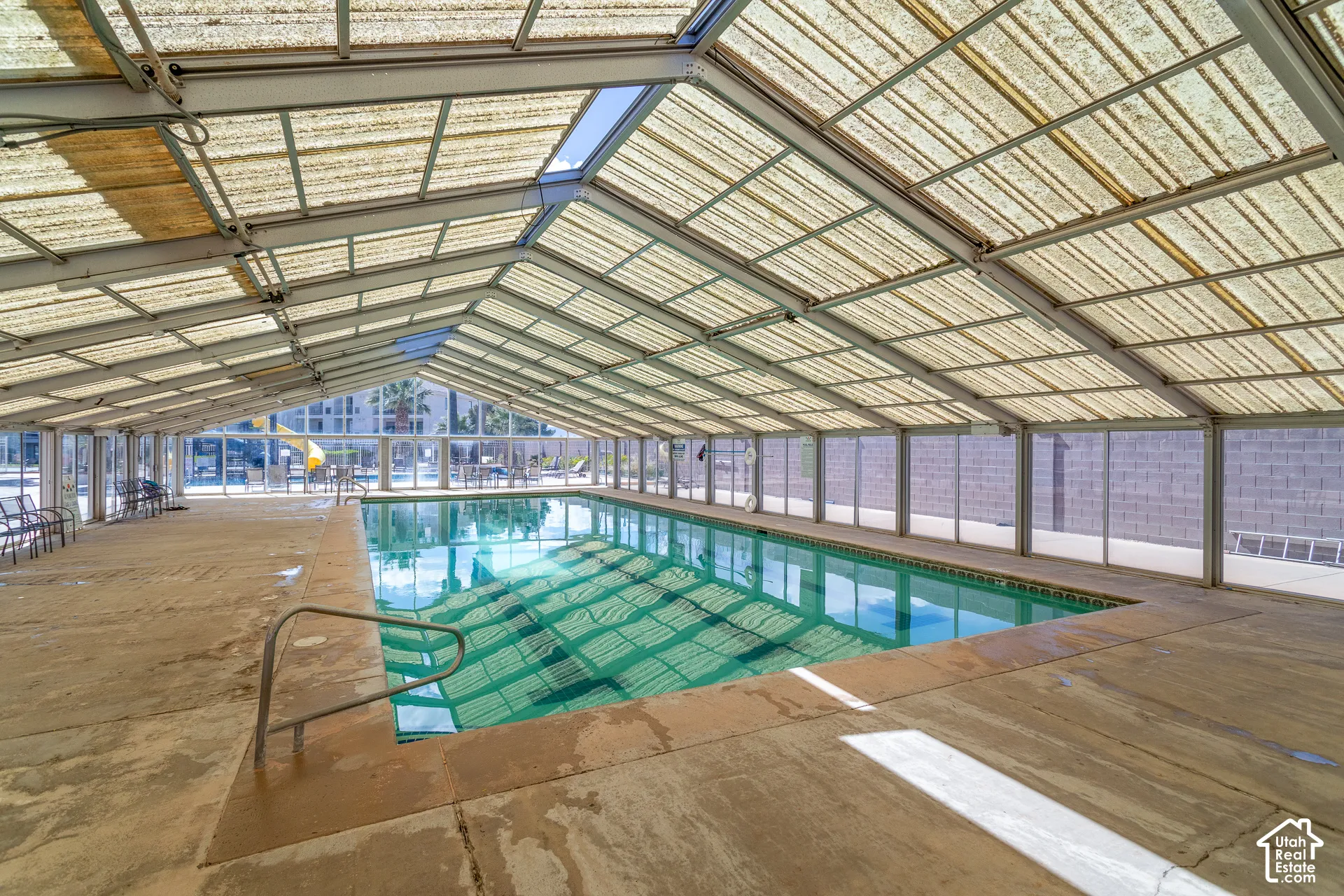 Enclosed swimming pool with a translucent vaulted ceiling, integrated skylights, and a concrete pool deck. Heated year round.