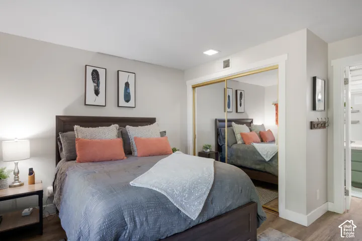 Bedroom featuring wood-finish flooring, mirrored closet doors, and recessed ceiling lighting