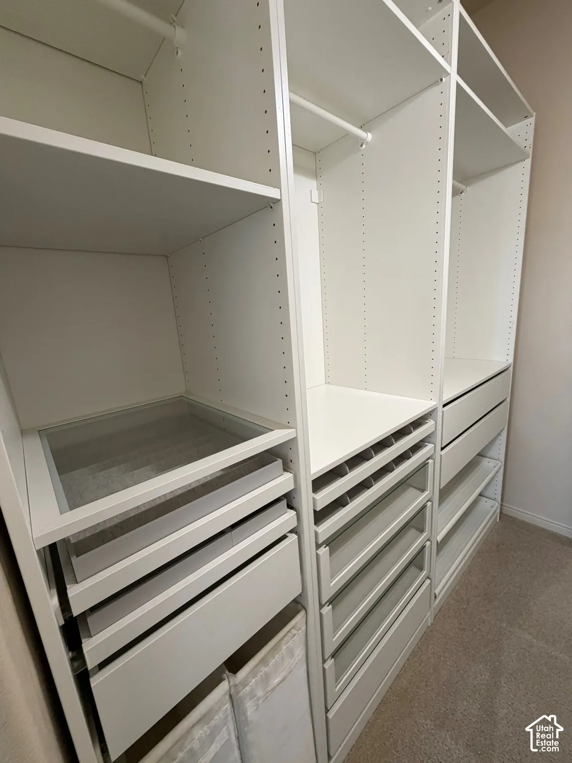 Integrated shelving system with multiple white shelves, various pull-out drawers, and clothing rods