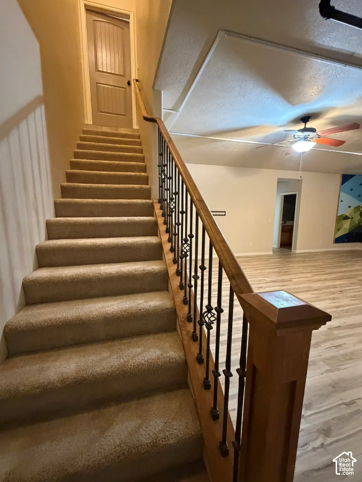 Staircase with carpeted treads and an ornate wrought iron and wood-finish railing