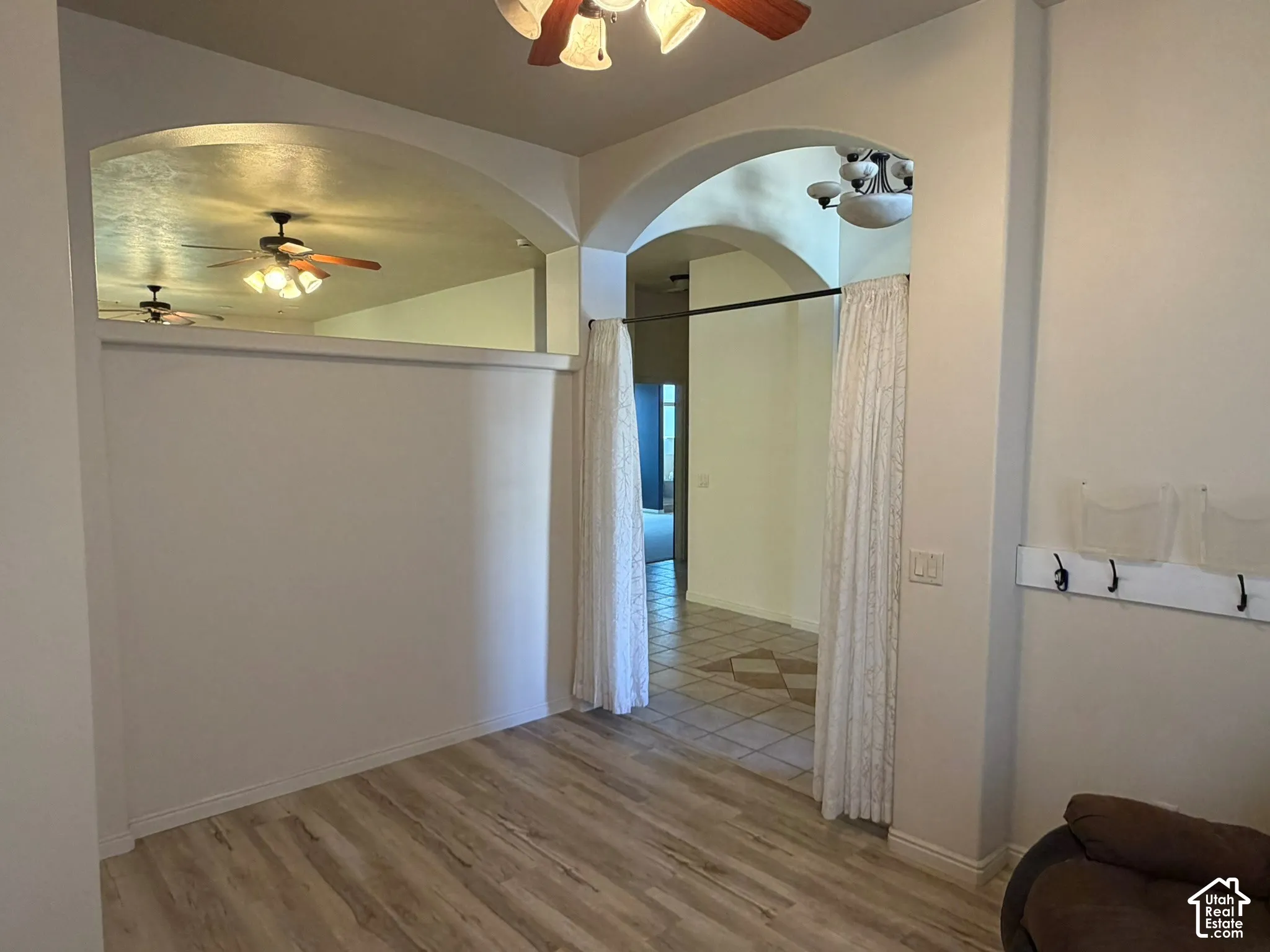 Archway entryways with decorative trim, wood-finish flooring, and a built-in coat rack