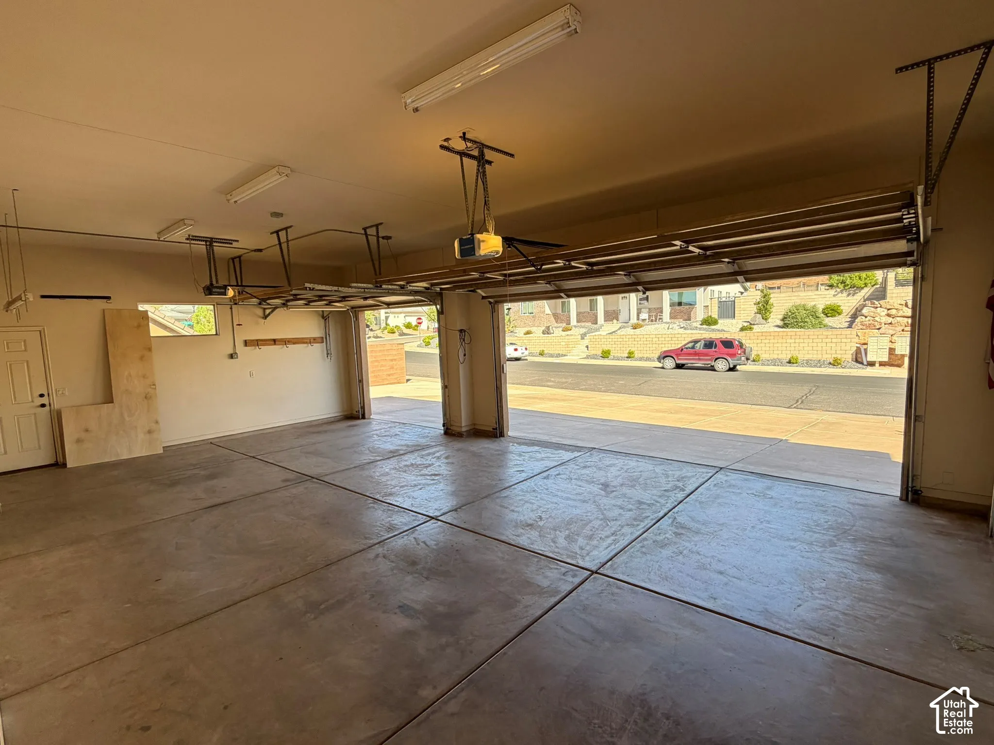 Spacious garage featuring a concrete floor, overhead fluorescent lighting, and two individual garage door openings