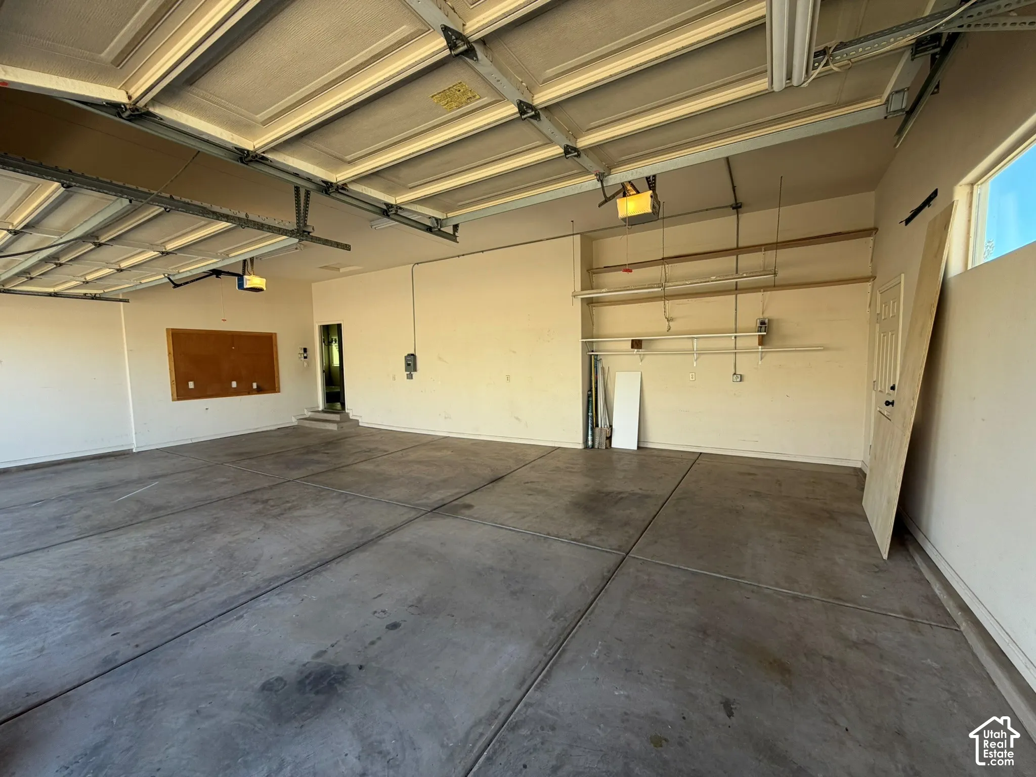 Spacious garage featuring concrete flooring, overhead lighting, and built-in shelving