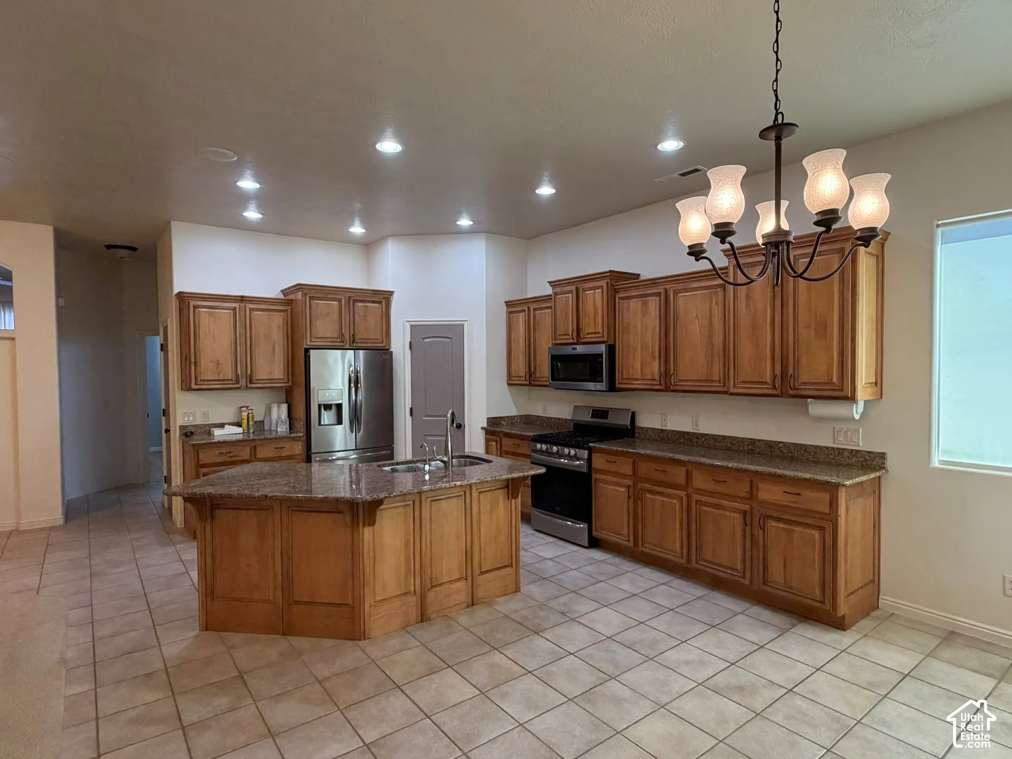 Kitchen featuring recessed lighting, a central island, wood cabinetry, stainless steel appliances, and tile flooring