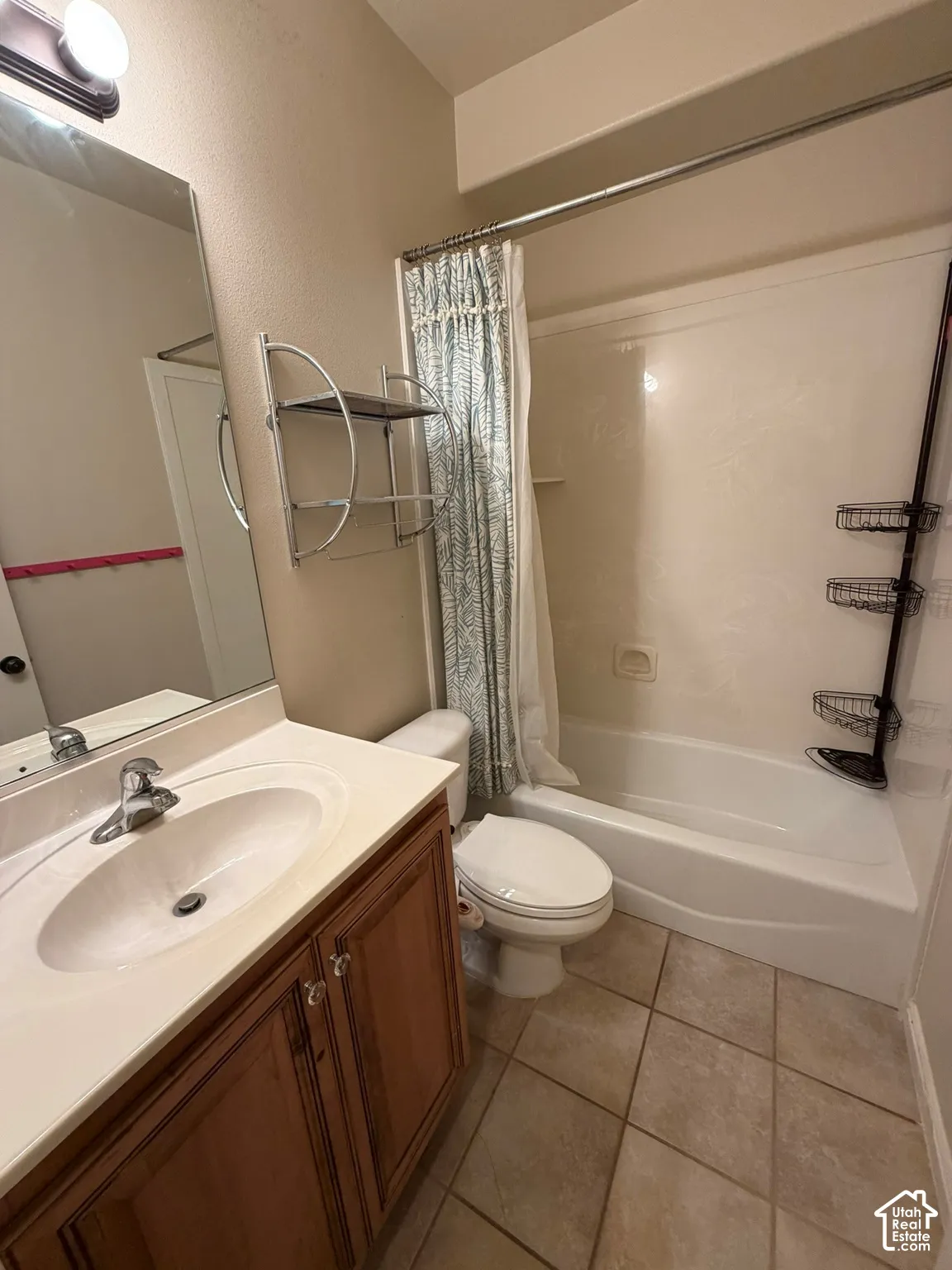 Bathroom featuring a vanity with wood-finish cabinetry, a built-in sink, and tile flooring