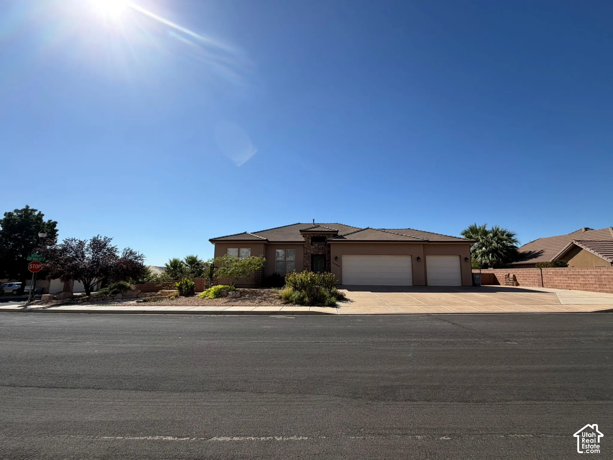 Stucco exterior with a tile roof, featuring an attached two-car garage and a paved driveway