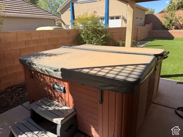 Spa with a protective cover, integrated steps, and wood-finish paneling, situated on a concrete patio