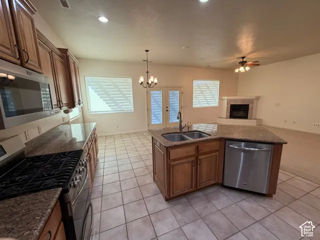 Kitchen featuring wood cabinetry, stainless steel appliances, granite countertops, and a central island with a double sink