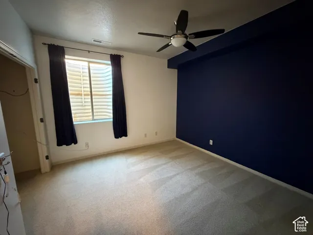 Wall-to-wall carpeting with a ceiling fan light fixture and a window with blinds