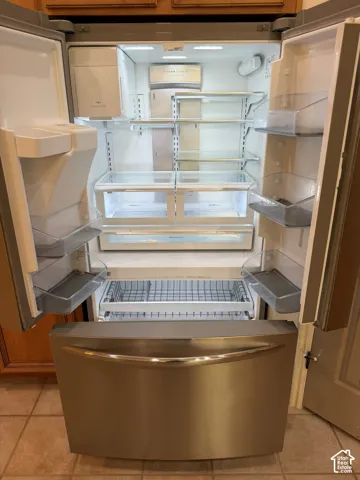 Stainless steel refrigerator with double French doors, interior shelving, clear crisper drawers, and a bottom freezer drawer