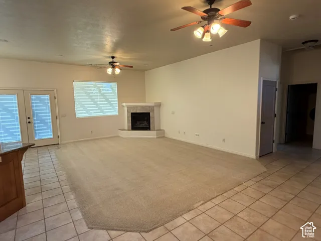 Spacious living area featuring a corner fireplace, multiple ceiling fans, and a combination of carpet and tile flooring