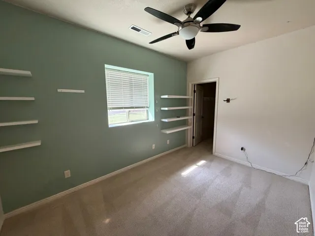 Wall-to-wall carpeting, ceiling fan, natural light window with blinds, and built-in floating shelves