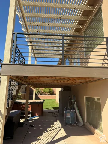 Upper-level deck with a slatted pergola, featuring black metal railings and wood-finish decking