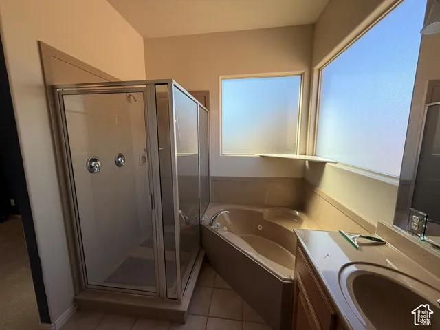 Glass-enclosed shower with chrome fixtures, jetted soaking tub, dual-pane frosted windows, and vanity with integrated sink