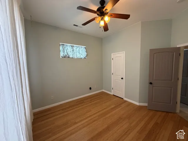 Hardwood flooring, ceiling fan with integrated lighting, window with exterior scenery, white interior door, and paneled interior door