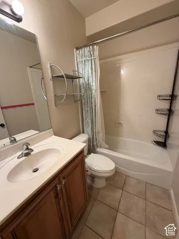 Bathroom featuring a vanity with wood-finish cabinetry, a built-in sink, and tile flooring