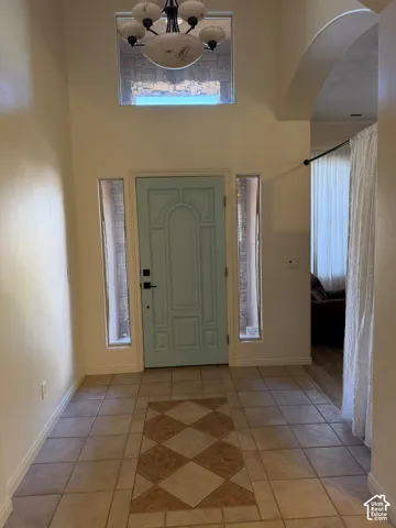 Two-story entryway featuring a decorative light fixture, transom window, and tile flooring with a patterned inlay
