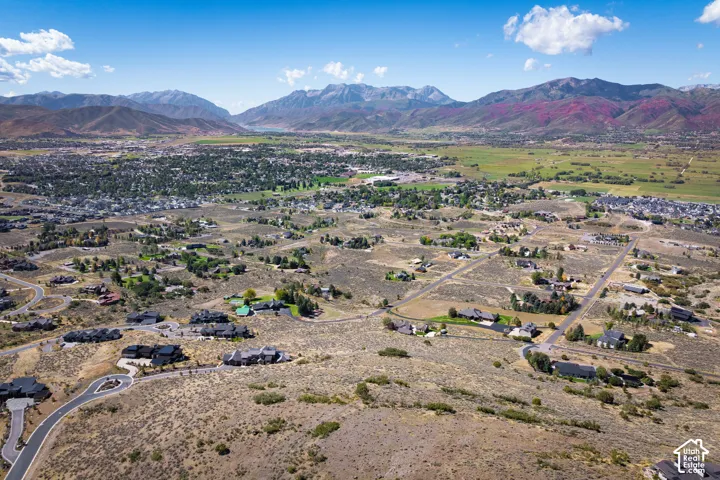 Expansive landscape featuring mountain ranges, scattered residential properties, and a distant town