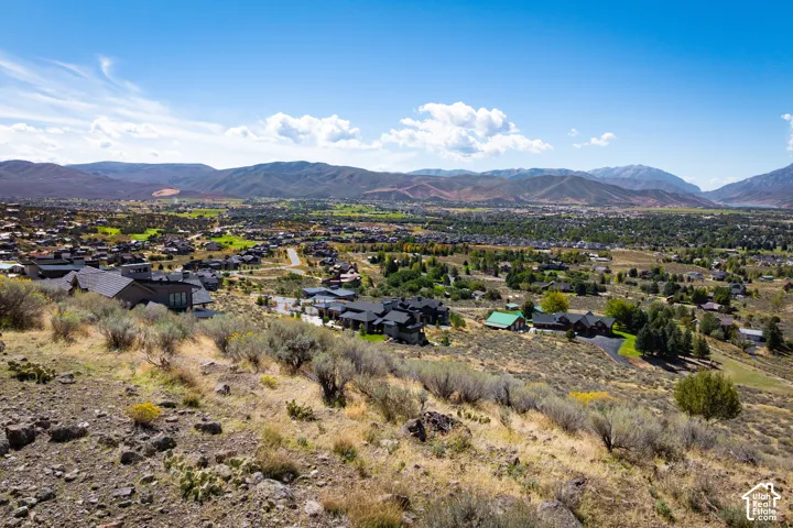 Expansive landscape featuring distant mountains and a valley with multiple residential properties