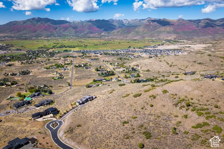Expansive mountain range backdrop, scattered residential developments, paved roadways, and natural arid landscaping