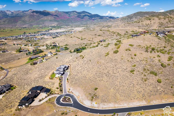 Expansive mountain terrain with winding paved roads, cul-de-sac, and distant residential developments