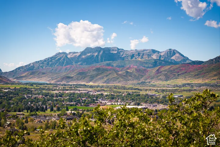Expansive mountain range backdrop with a verdant valley and distant water body