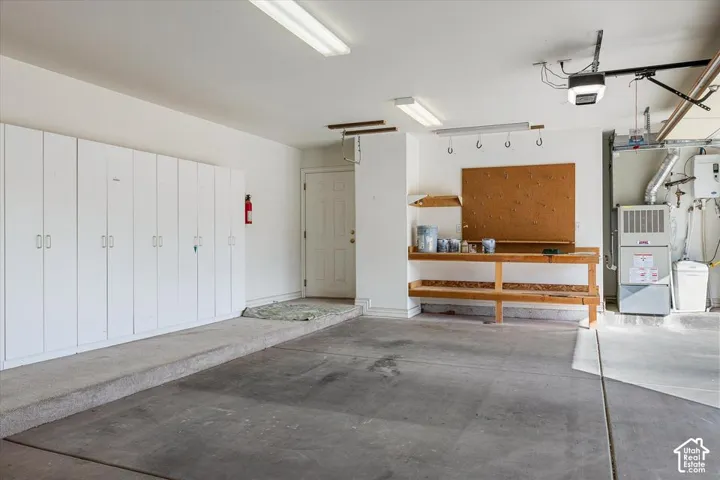 Concrete flooring with a built-in workbench, extensive cabinetry, and overhead fluorescent lighting