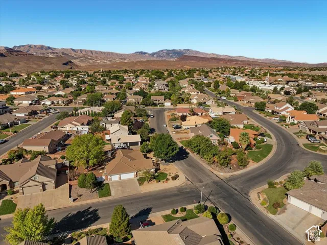 Residential neighborhood with mature trees, paved streets, and distant mountain backdrop
