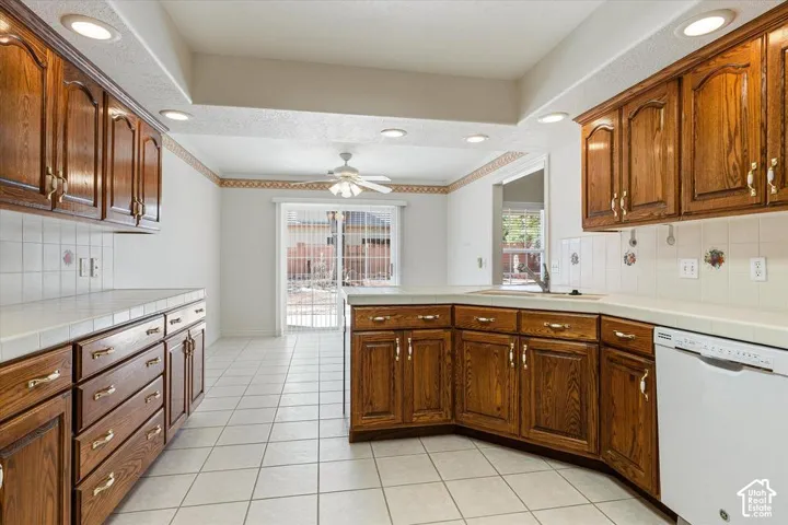 Kitchen featuring wood cabinetry, white tile flooring, recessed lighting, a ceiling fan, and sliding glass doors