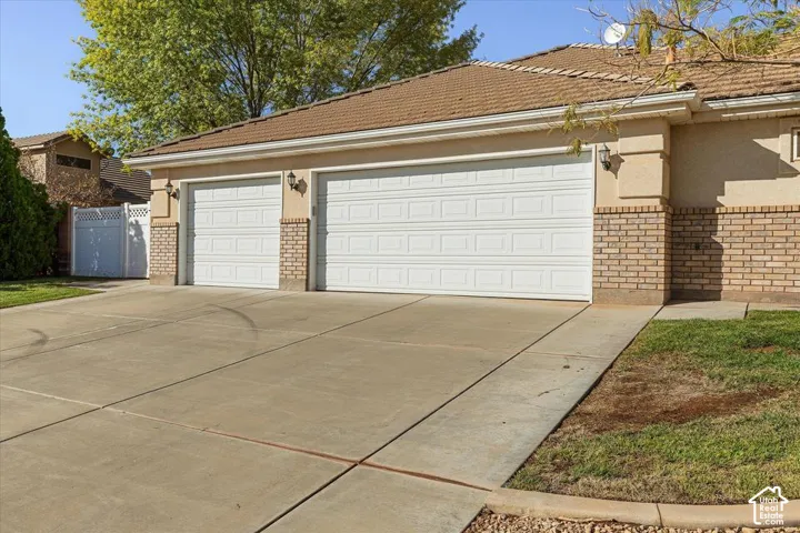 Two-car garage with white panel doors, exterior sconce lighting, and a brick veneer facade