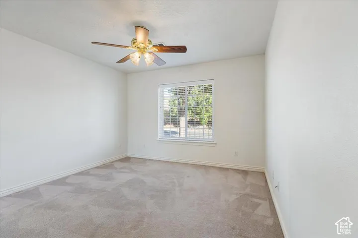 Recessed window with horizontal blinds, overhead ceiling fan with integrated lighting, and neutral tone carpeting