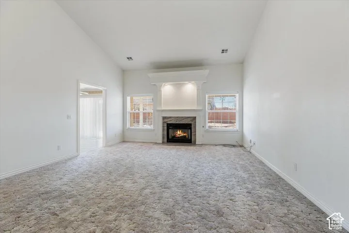 Spacious living area featuring a vaulted ceiling and textured carpet