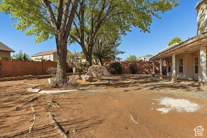 Expansive backyard featuring mature trees, a concrete patio, and a covered porch with supporting columns