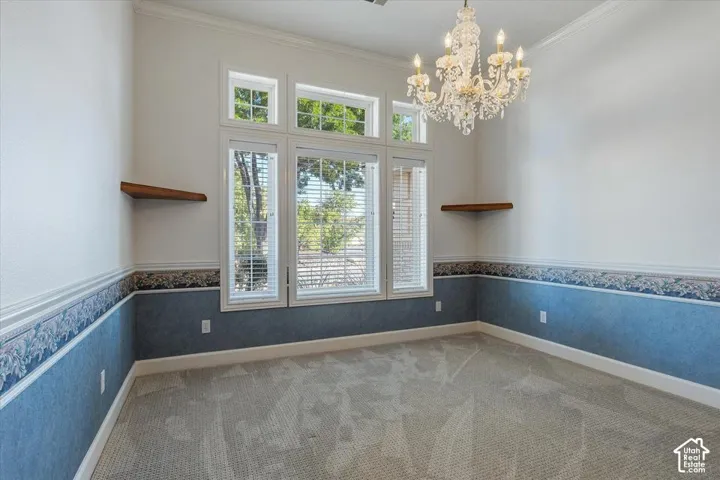 Large picture window with transom glass, ornate chandelier, crown molding, and two built-in floating shelves