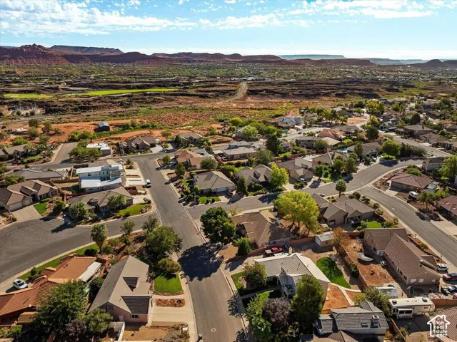 Residential neighborhood with varied architectural styles and mature landscaping, surrounded by desert terrain and distant red rock formations