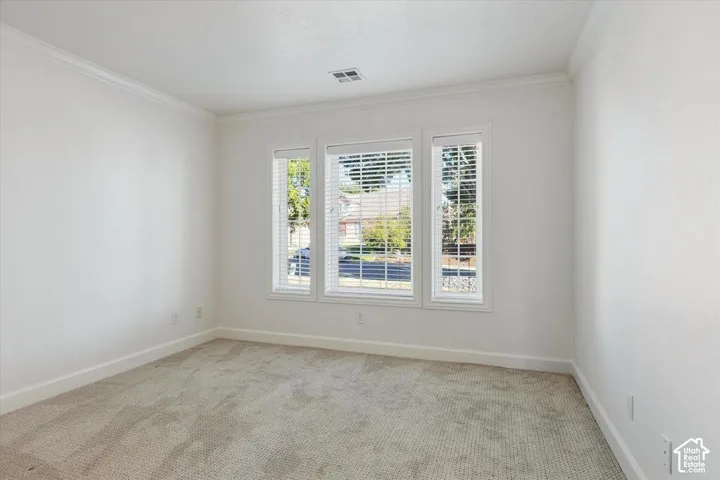 Crown molding, neutral tone carpet, triple window array, and horizontal blinds